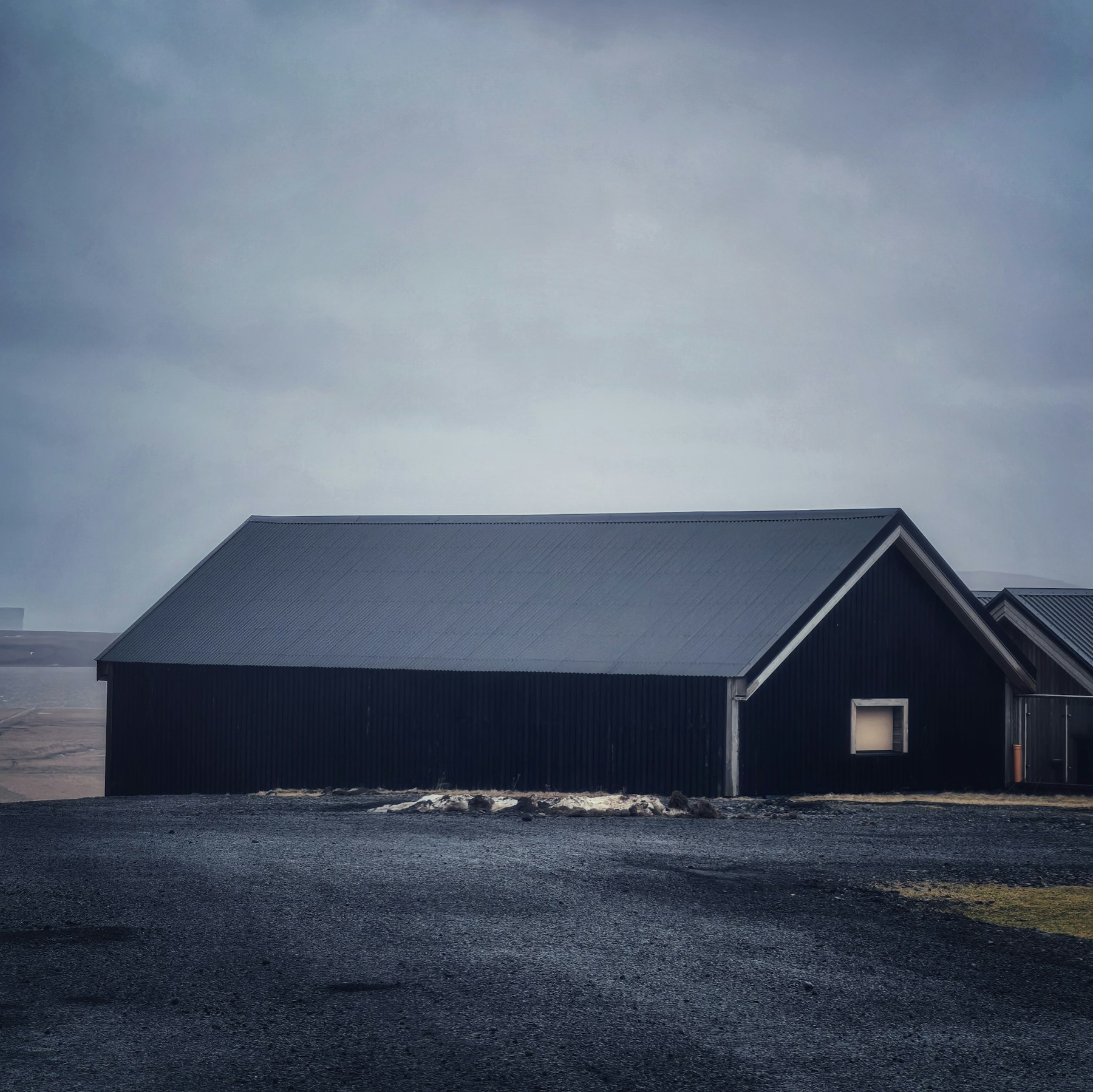 Contemporary dark timber house beneath a cloudy sky